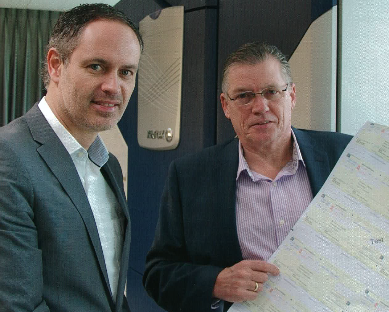 Twee zakelijke professionals tonen een vel met uitgeprinte acceptgiro’s in een kantooromgeving, als voorbeeld van papieren betaalverzoeken.