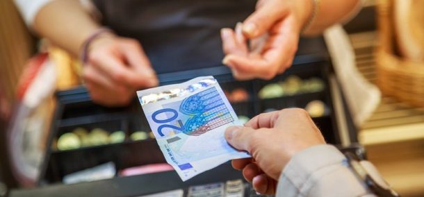 Vrouw die bij een kass met contant geld betaalt.