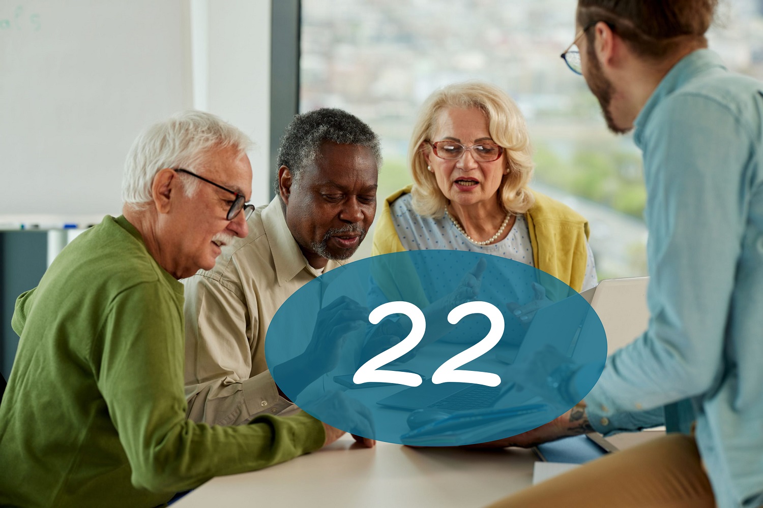 Groep oudere mensen krijgt uitleg van jongere man bij laptop en smartphone tijdens digitale vaardigheidstraining en groot cijfer 22 in blauwe cirkel.