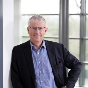 Paul Scholten, CEO van Buckaroo, staat ontspannen met Ã©Ã©n hand in de zij en kijkt vriendelijk in de camera in een lichte kantooromgeving.